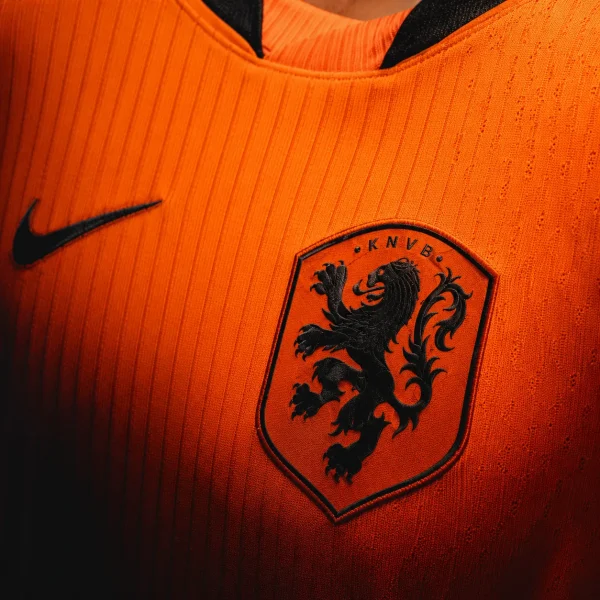 Netherlands football crest on orange jersey fabric background