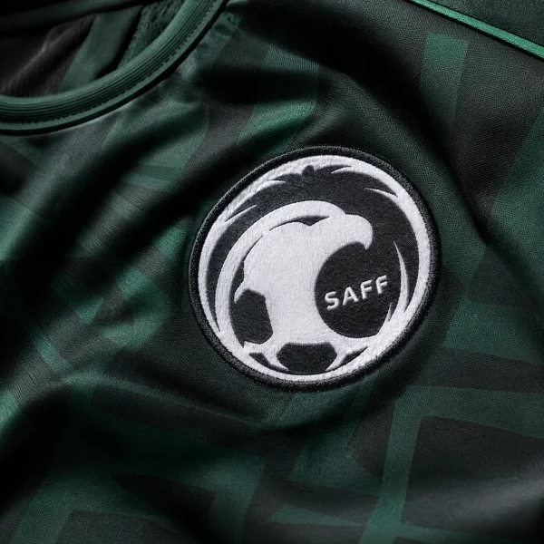 Saudi Arabia football crest on green jersey fabric background