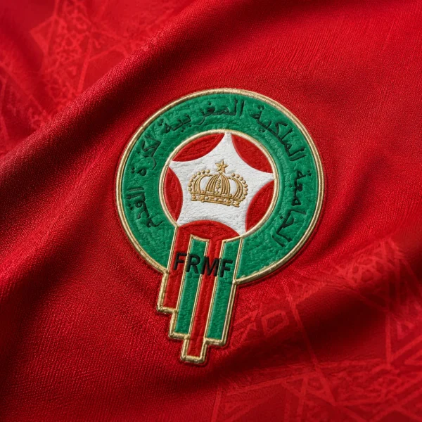 Morocco football crest on red jersey fabric background